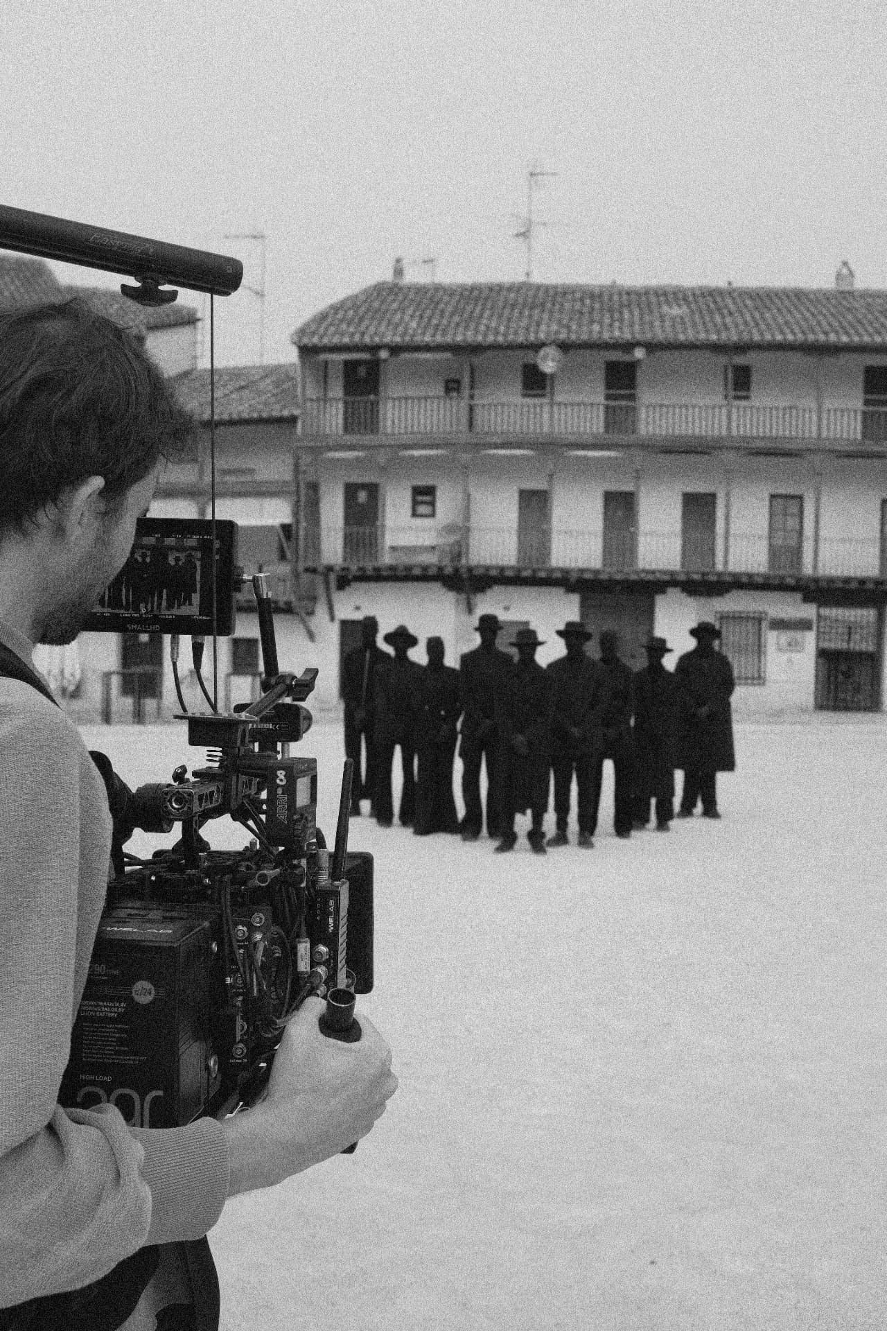 Camera operator filming a group of performers in a Spanish plaza